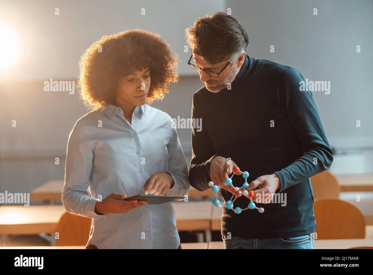 Geschäftsfrau im Gespräch mit einem Kollegen, der ein Musterobjekt im Amt hält Stockfoto