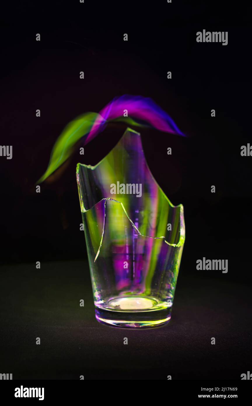 Studioaufnahme aus gebrochenem Glas, das grünes und violettes Licht reflektiert Stockfoto