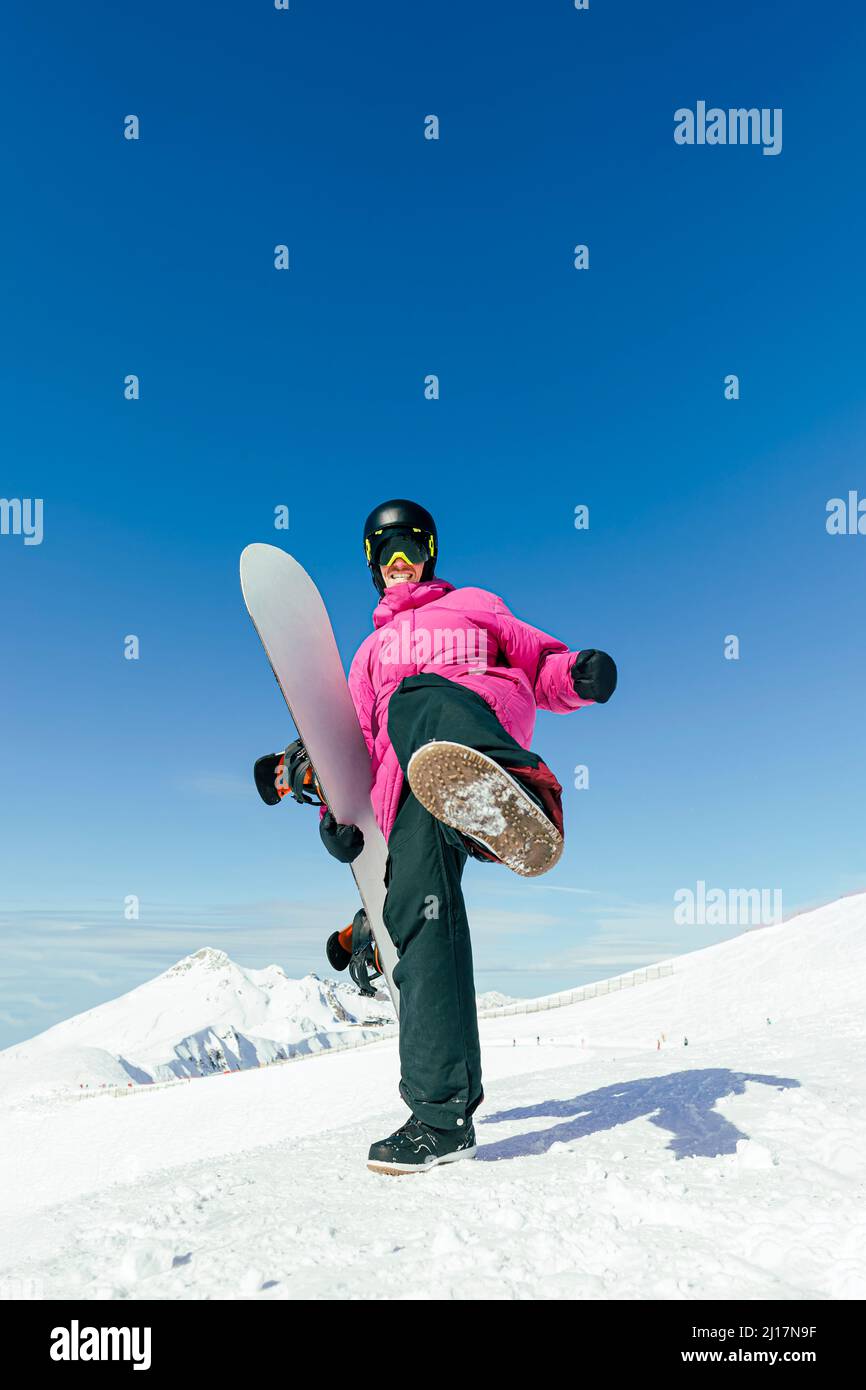 Mann mit Snowboard-Treten, der auf verschneiten Bergen steht Stockfoto