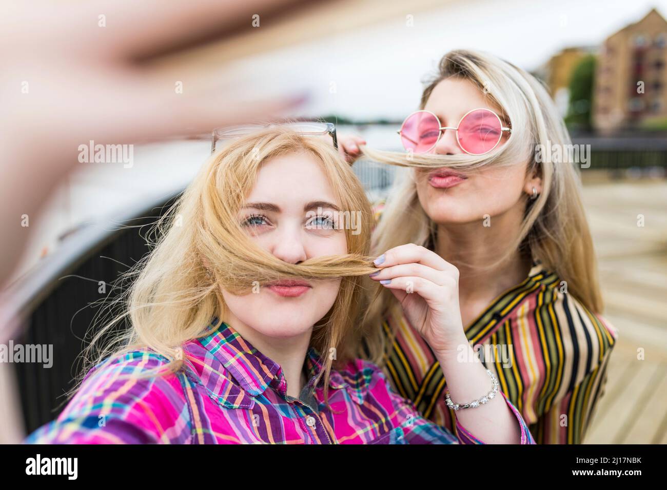 Lächelnde blonde Teenager, die Schnurrbärte machen und Selfie machen Stockfoto