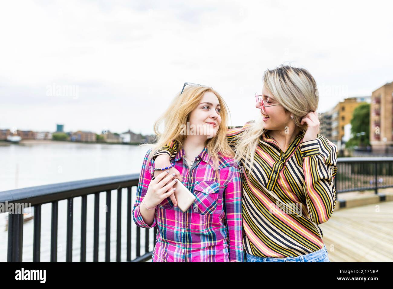 Fröhliche Teenager mit blonden Haaren laufen auf der Promenade zusammen Stockfoto