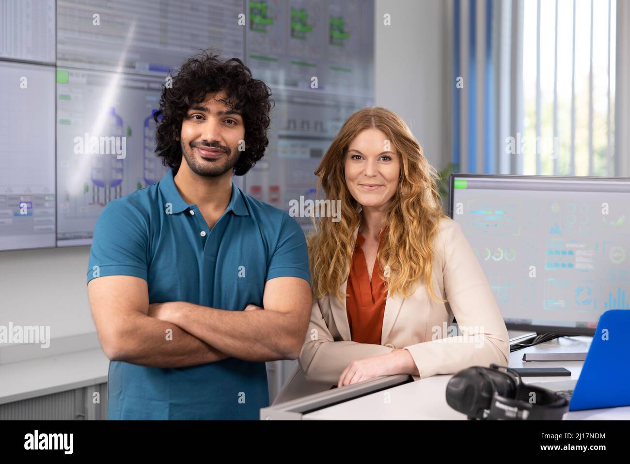 Lächelnde Geschäftsfrau mit Techniker am Schreibtisch im Kontrollraum Stockfoto