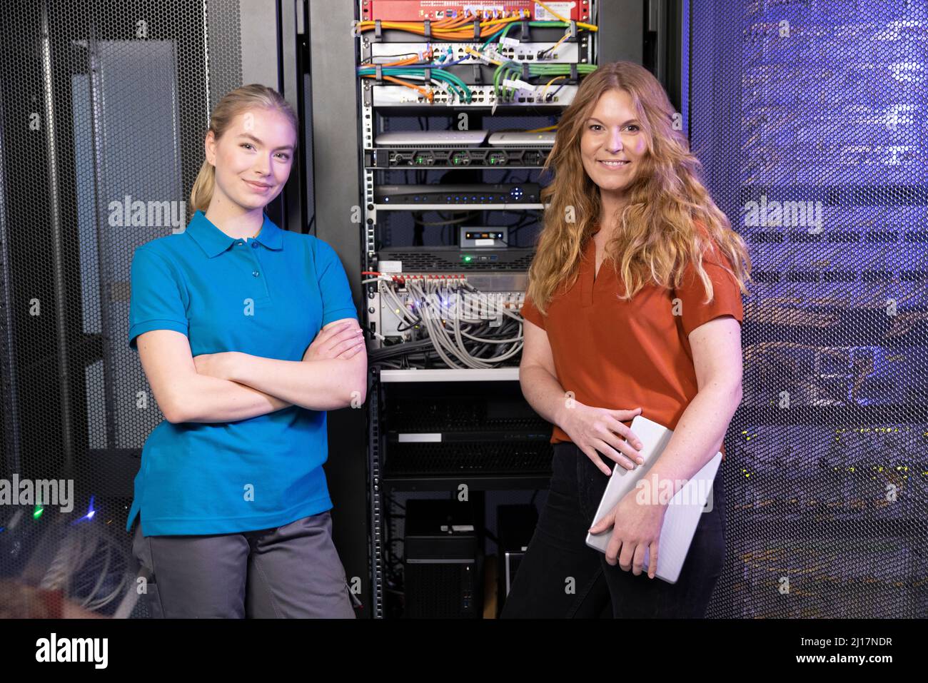 Lächelnde IT-Techniker stehen im Serverraum Stockfoto