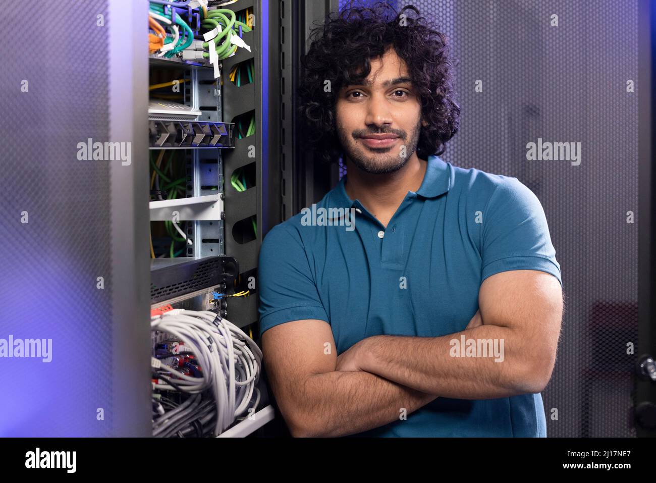 Techniker mit gekreuzten Armen, der im Serverraum steht Stockfoto
