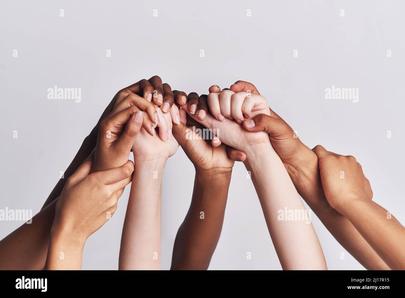 Insgesamt abwechslungsreich. Aufnahme einer Gruppe von Händen, die sich vor weißem Hintergrund aneinander halten. Stockfoto