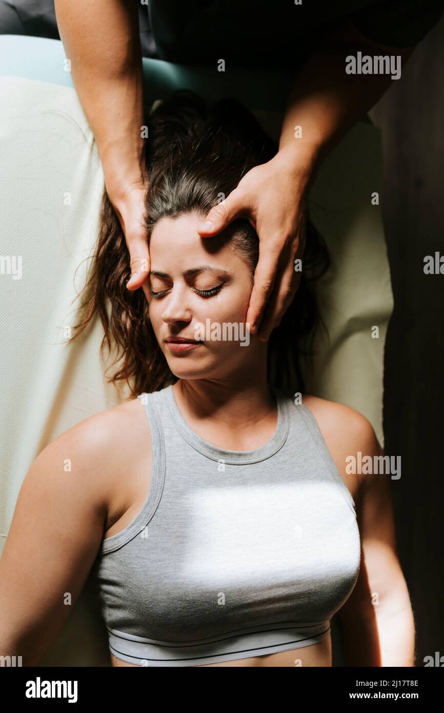 Physiotherapeut gibt Kopfmassage für die Frau, die mit geschlossenen Augen liegt Stockfoto