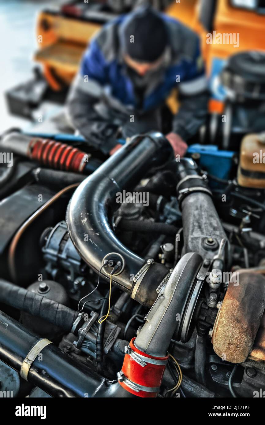 Der Schlosser oder Mechaniker repariert den Motor des Staplers in der Werkstatt. Autowartung. Autoservice. Hintergrund. Stockfoto