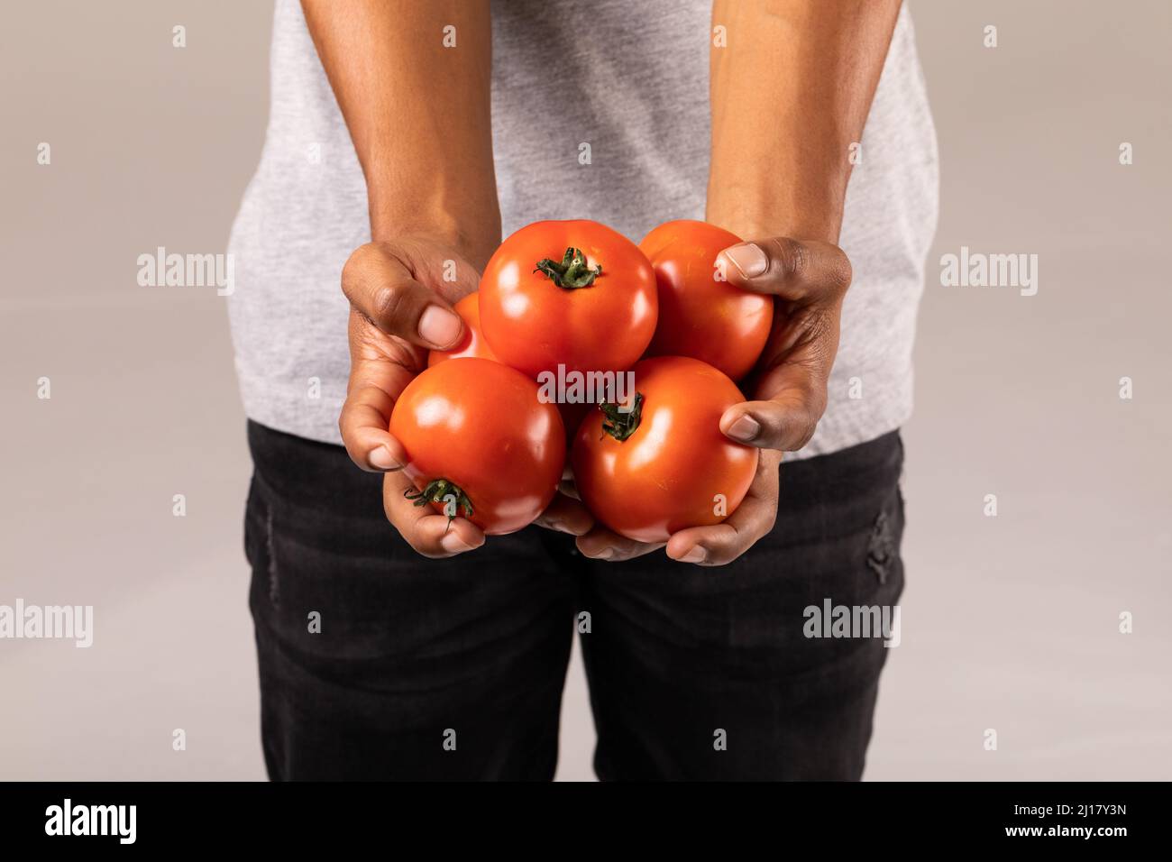 Mittelteil eines Mannes mit frischen roten Tomaten, der vor weißem Hintergrund steht Stockfoto