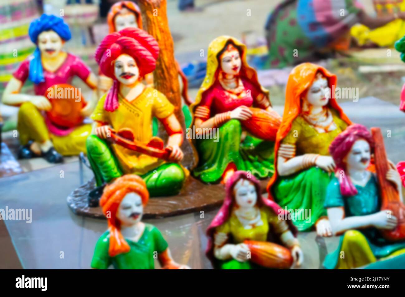 Verschwommenes Bild von bunten männlichen und weiblichen Terrakotta-Puppen in traditionellen indischen Kleidern, Musikinstrumente spielend, hergestellt in Krishnanagar, N Stockfoto