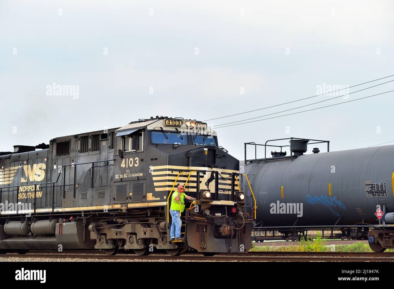 BENSENVILLE, Illinois, USA. Ein Arbeiter fährt auf den Stufen einer Lokomotive der Norfolk Southern Railway, die einen Güterzug der Canadian Pacific Railway führt. Stockfoto