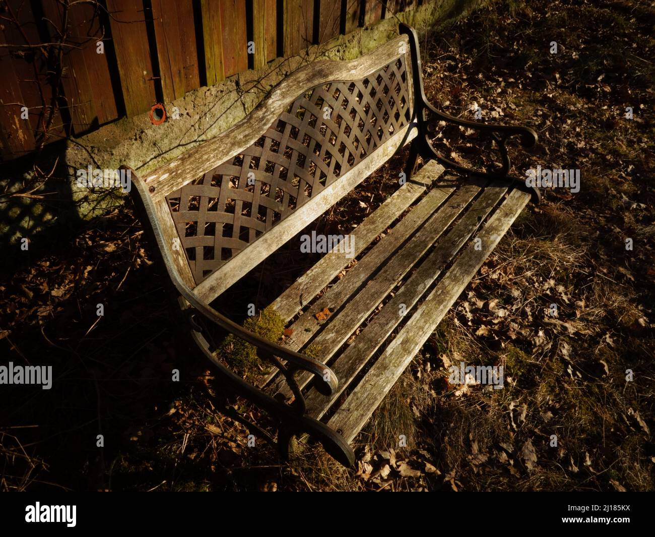 Eine alte Vintage schmiedeeiserne Gartenbank mit dekorativen Details im Design und einer schönen geflochtenen Rückenlehne, ein ruhiger Ort auf dem Land. Stockfoto