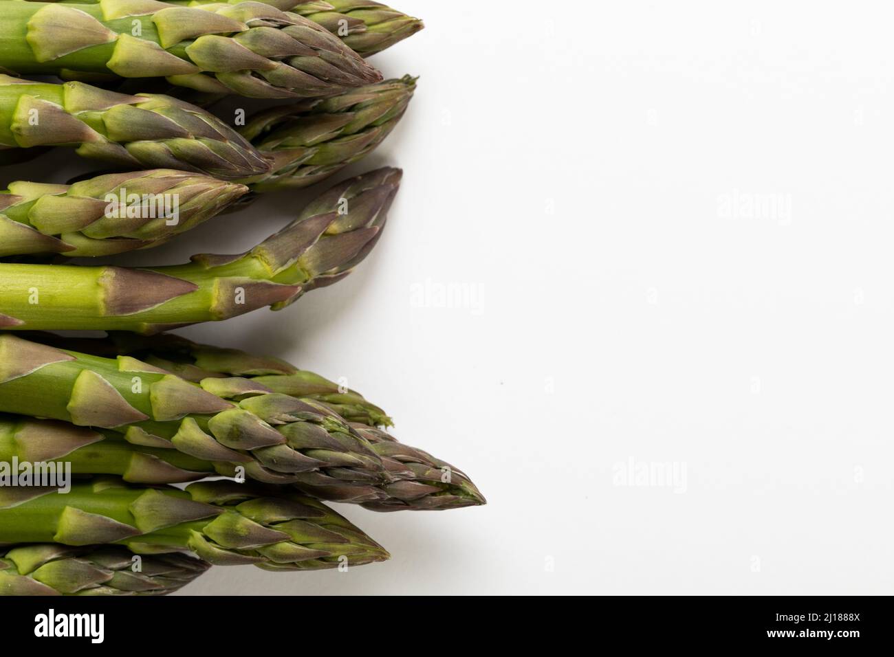 Nahaufnahme von rohem Gemüse aus grünem Spargel über dem Kopf durch einen Kopierbereich vor weißem Hintergrund Stockfoto