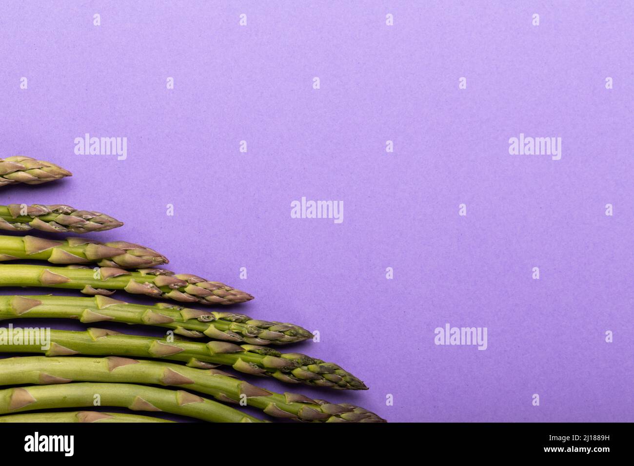 Overhead-Ansicht des Kopierraums mit rohem Spargel nebeneinander auf violettem Hintergrund Stockfoto