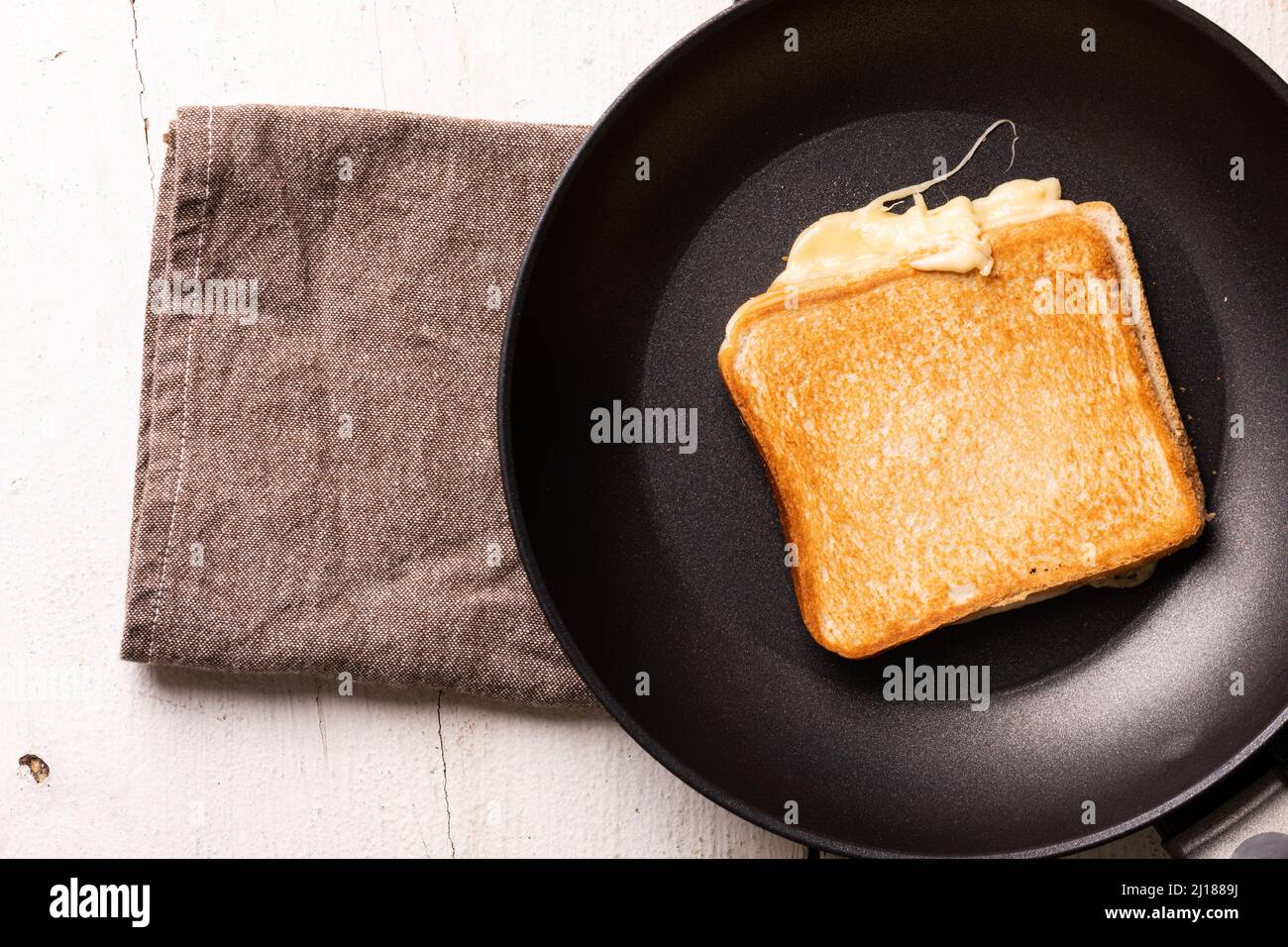Blick von oben auf das Frischkäse-Sandwich in der Pfanne auf Serviette über dem weißen Tisch Stockfoto