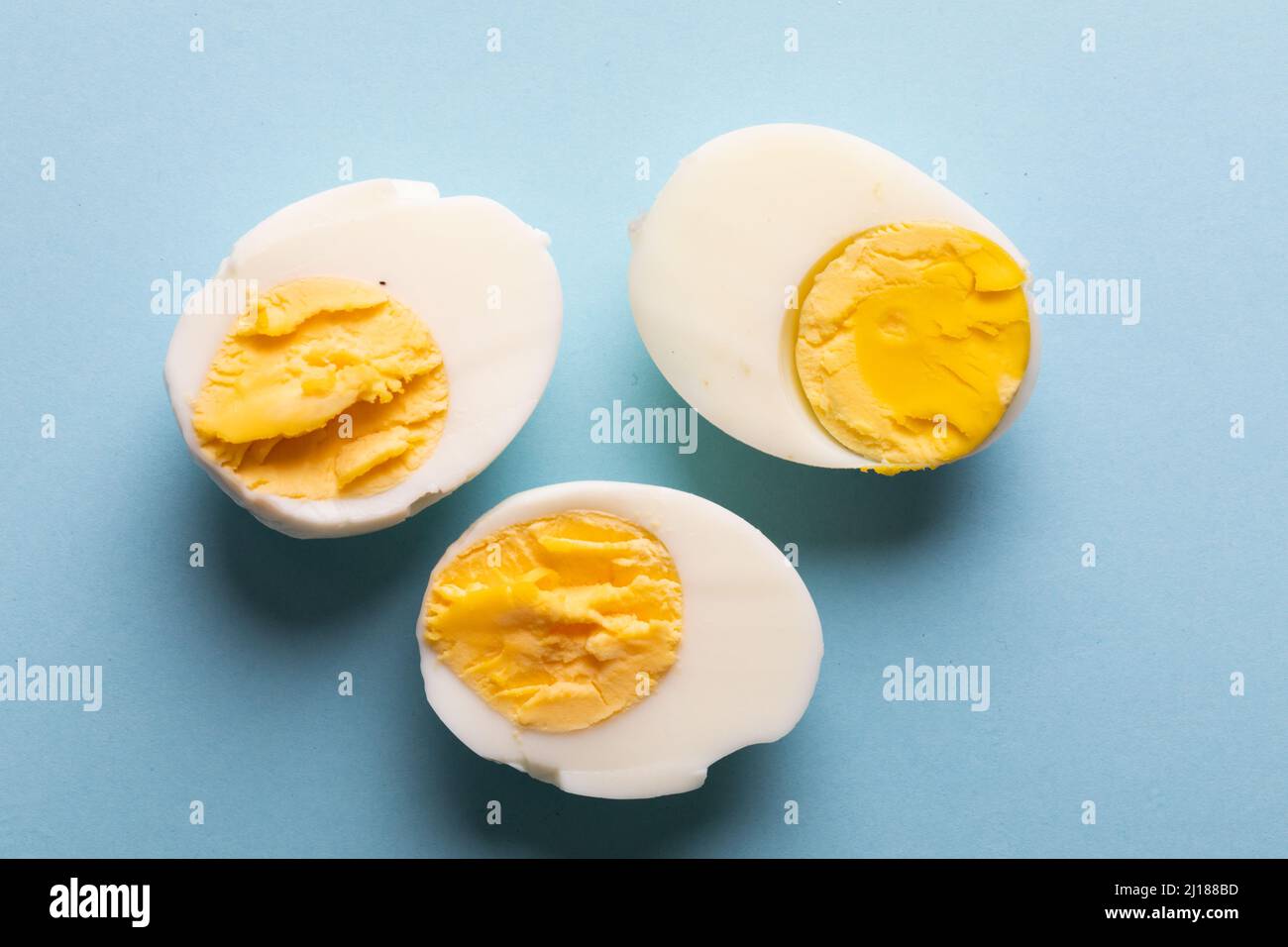Blick von oben auf frisch gekochte weiße Eierhälften auf blauem Hintergrund Stockfoto