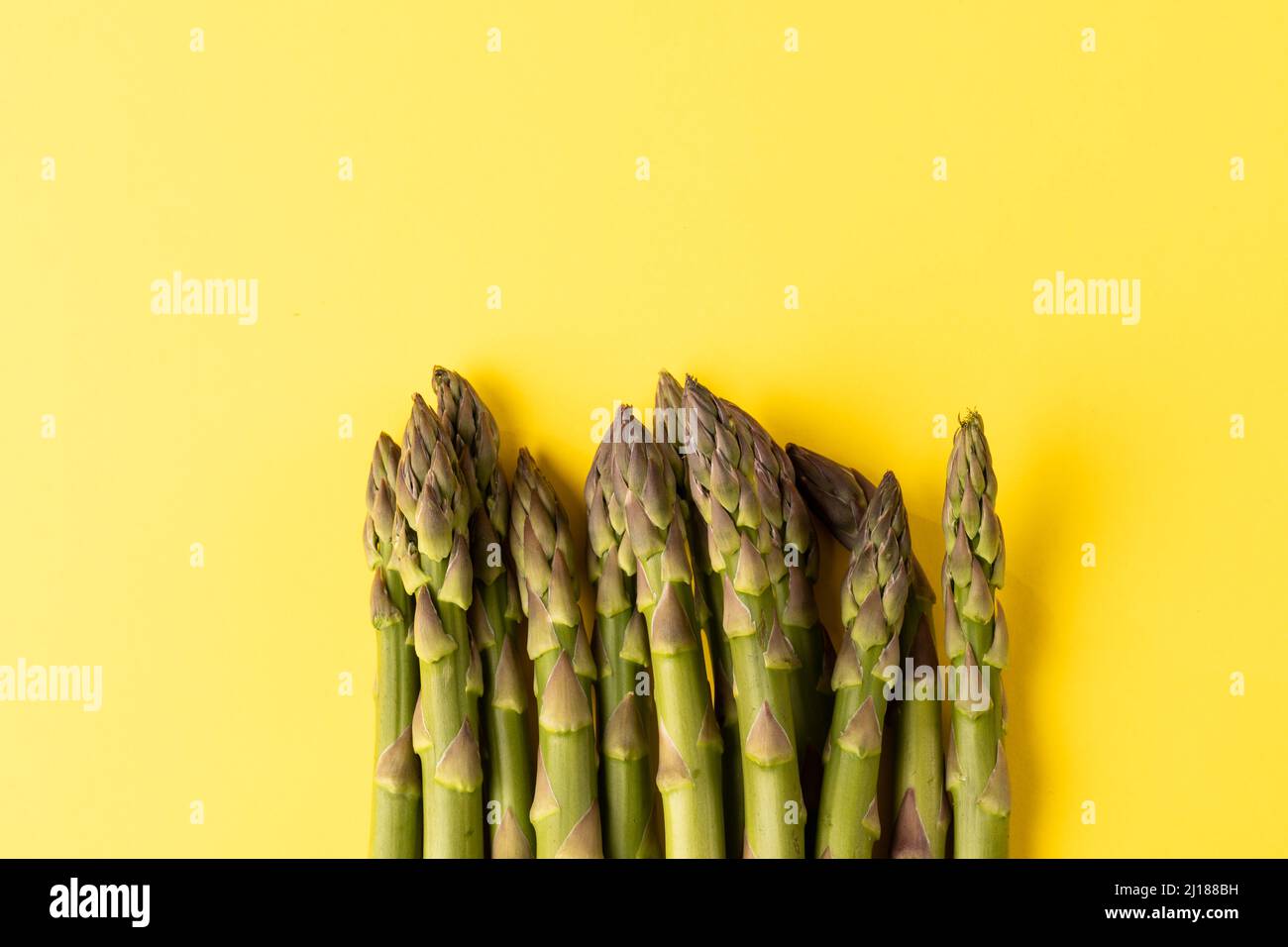 Direkt über Ansicht von rohem grünem Spargelgemüse durch Kopierfläche vor gelbem Hintergrund Stockfoto