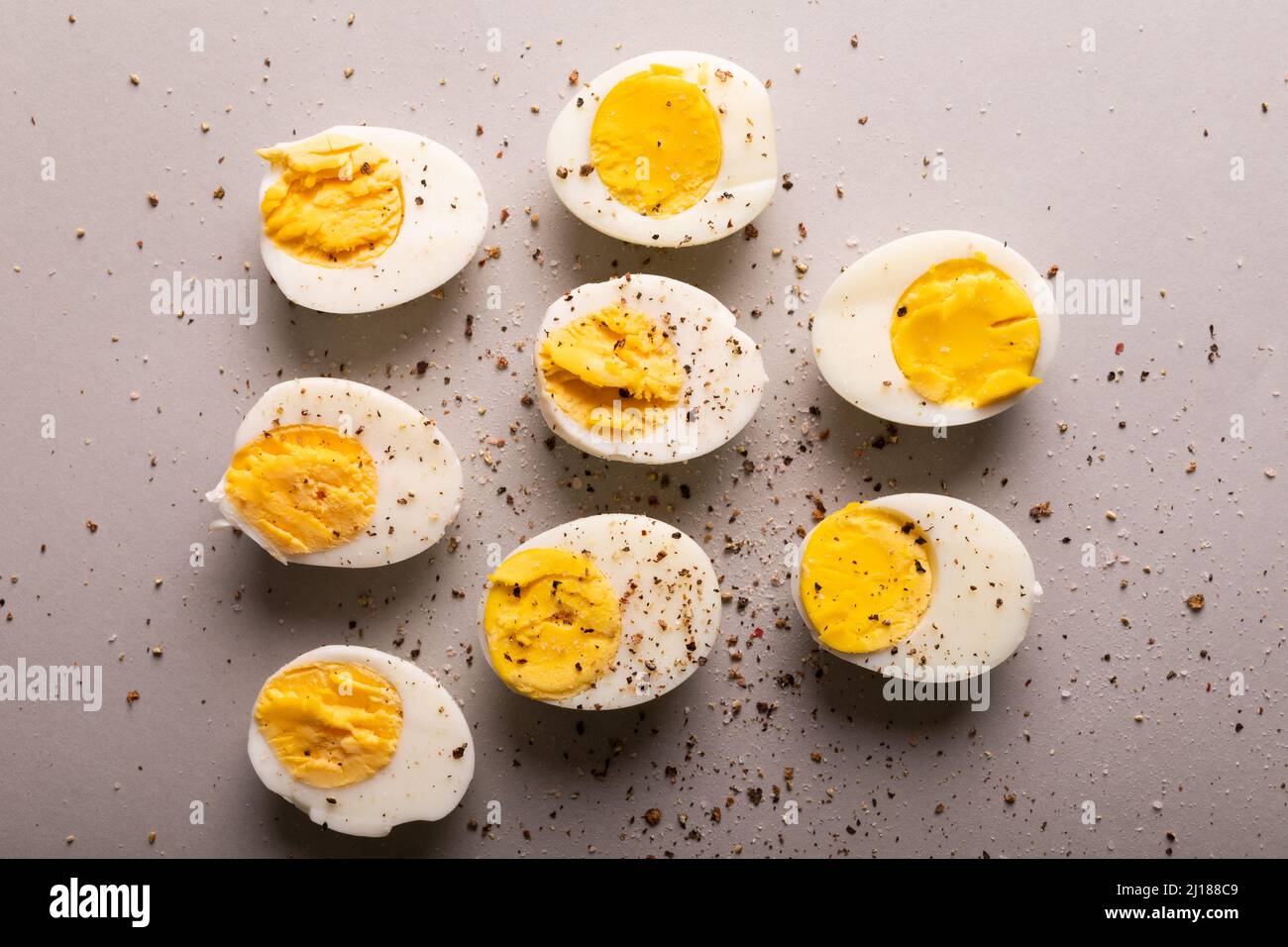 Blick von oben auf frisch gekochte weiße Eier mit Pfefferkorn-Gewürzen auf grauem Hintergrund Stockfoto