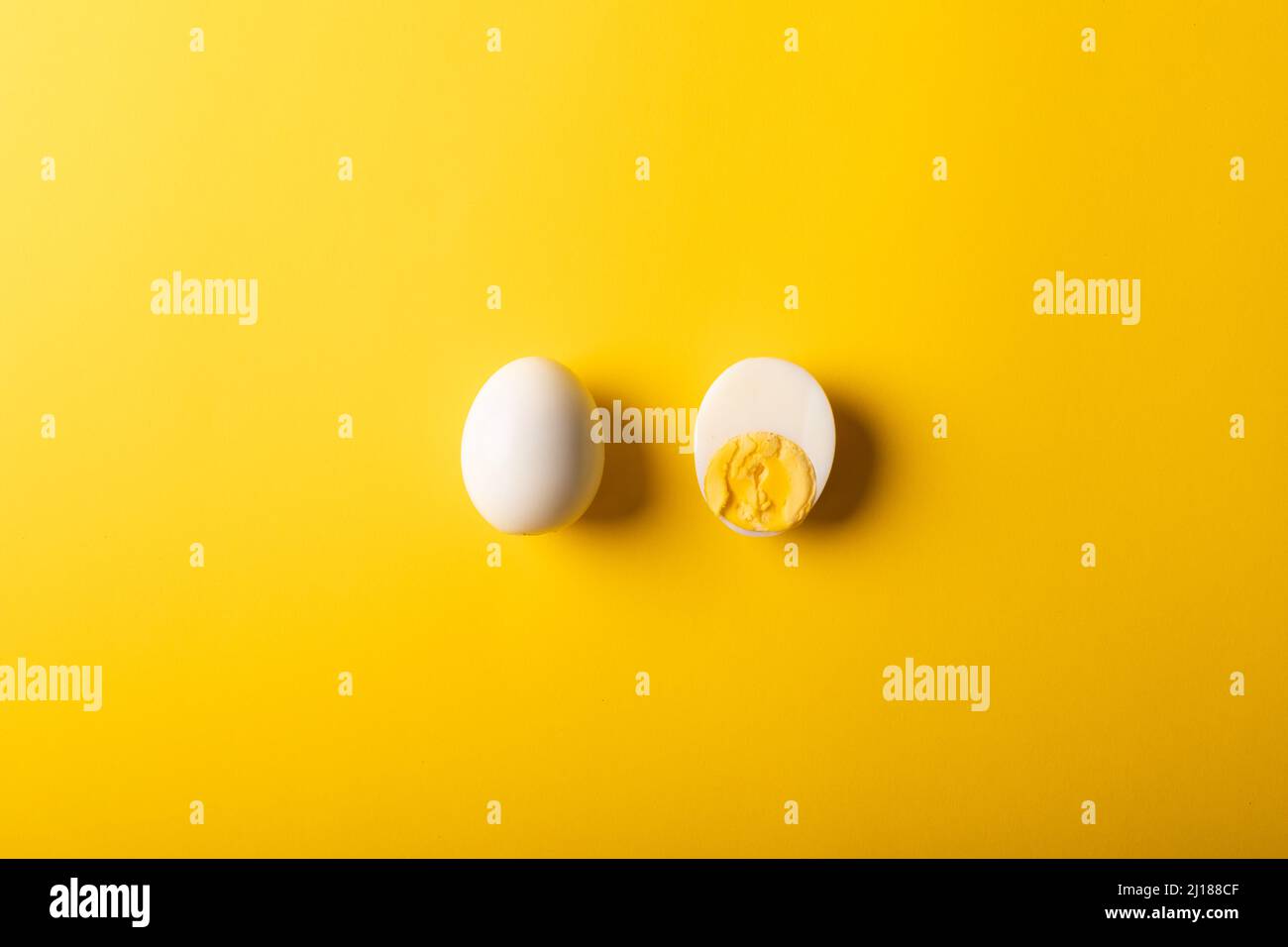 Direkt über dem Bild von frischen weißen Eiern, die durch einen Kopierraum vor gelbem Hintergrund gekocht werden Stockfoto