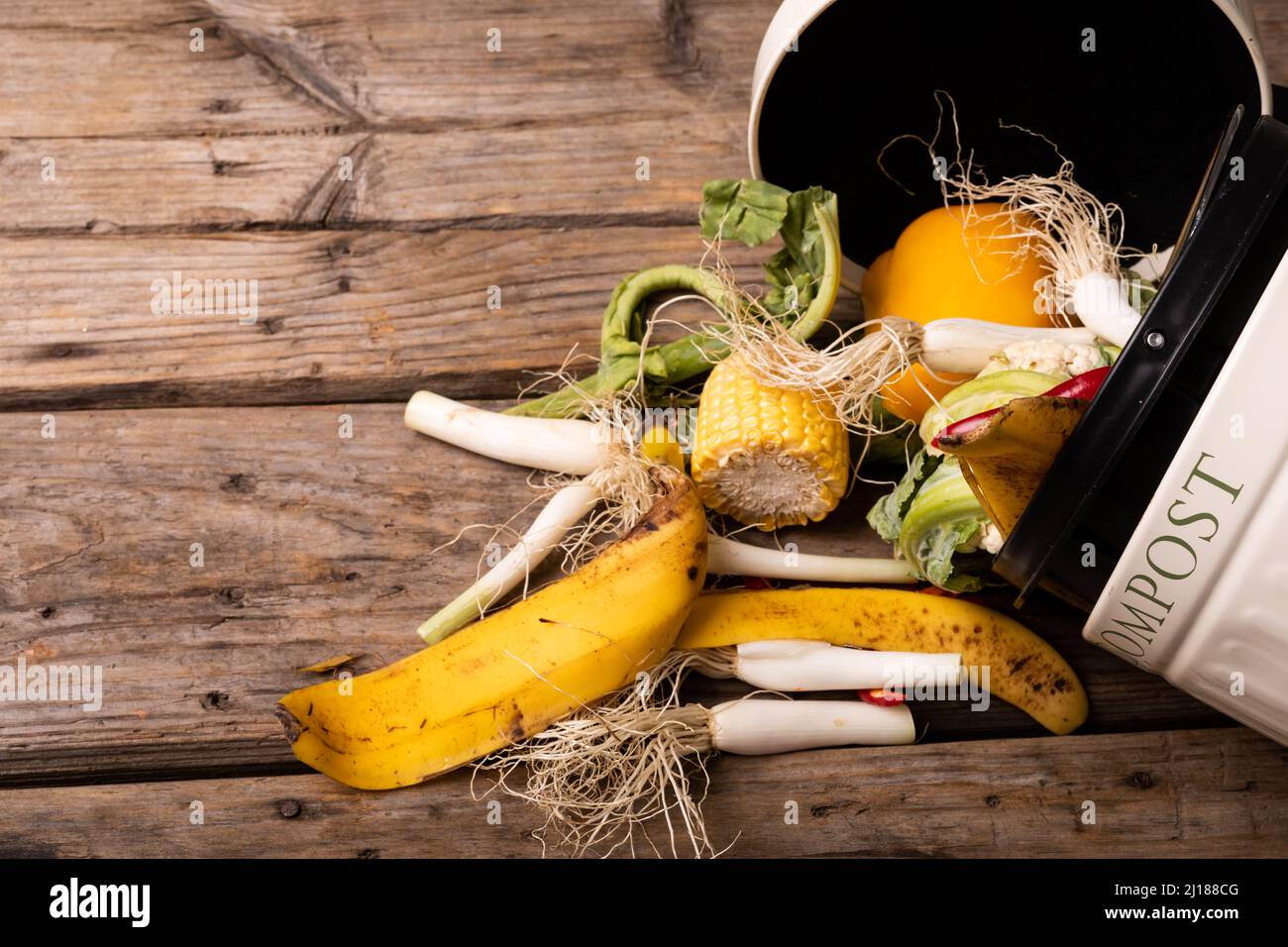 Deckenansicht von verschütteten organischen Abfällen im Kompostbehälter über dem Holztisch Stockfoto