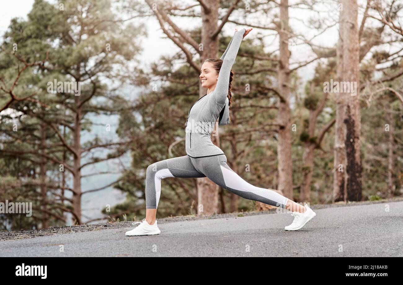 Strecken Sie sich zu einem stärkeren, schlankeren und gesünderen Sie. Aufnahme einer sportlichen jungen Frau, die ihren Körper während des Trainings im Freien dehnt. Stockfoto