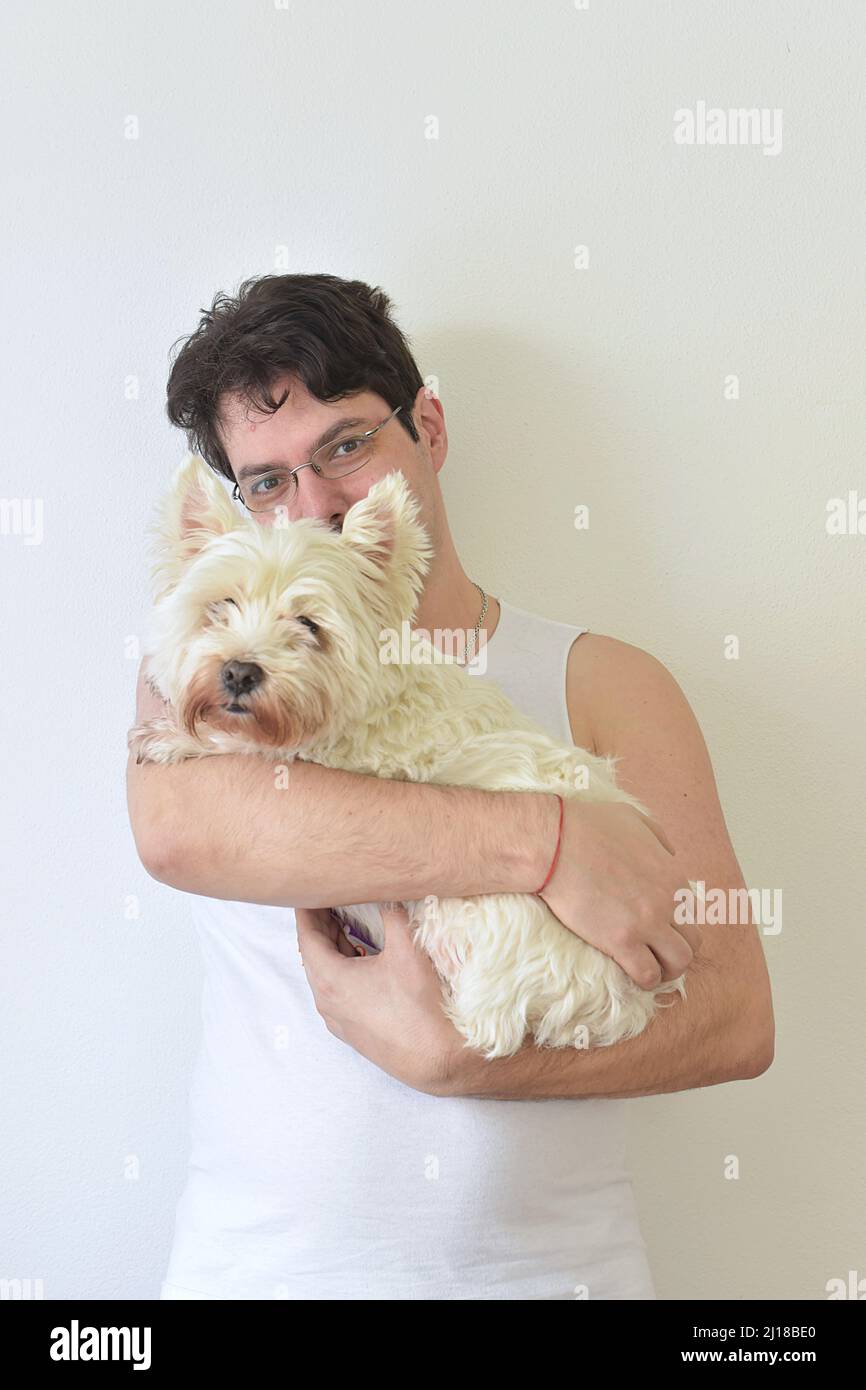 Mann, der einen weißen Hund in den Armen hält Stockfoto