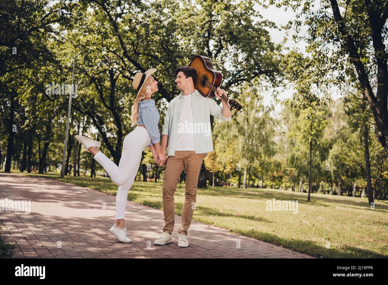 In voller Länge Körpergröße Ansicht von zwei attraktiven fröhlichen Paar trägt Gitarre Spaß verbringen Zeit an der frischen Luft im Freien Stockfoto