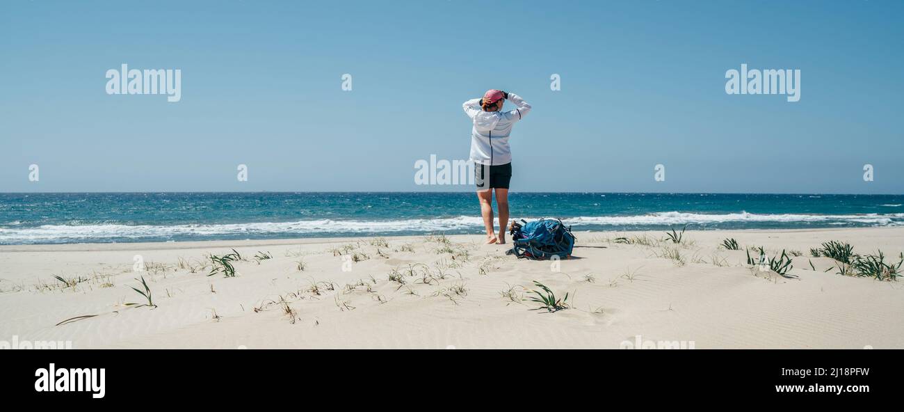 Backpacker Weibchen auf dem Strand der Sanddünen von Patara genießen das windige Mittelmeer während des Lykischen Weges Trekking. Berühmte Likya Yolu türkische Route Stockfoto