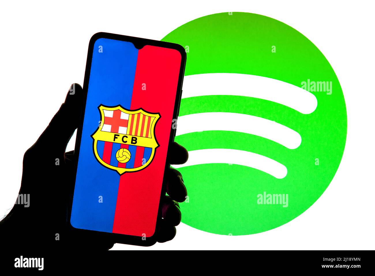In dieser Abbildung ist ein Football Club Barcelona (FCB)-Logo auf einem Smartphone mit einem Spotify-Logo im Hintergrund zu sehen. Stockfoto