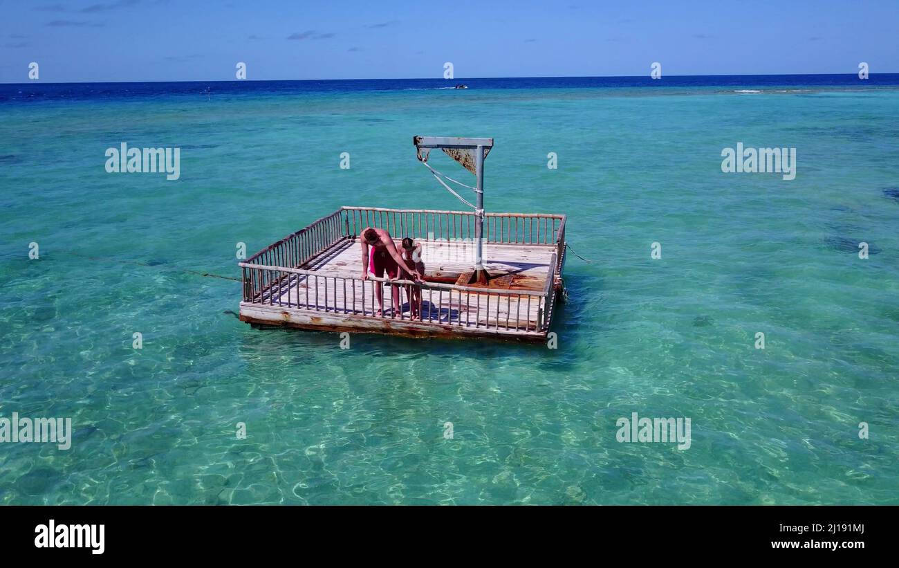 Ein junges Paar in Strandkleidung, das auf dem schwimmenden Dock auf Rasdhoo Island steht Stockfoto