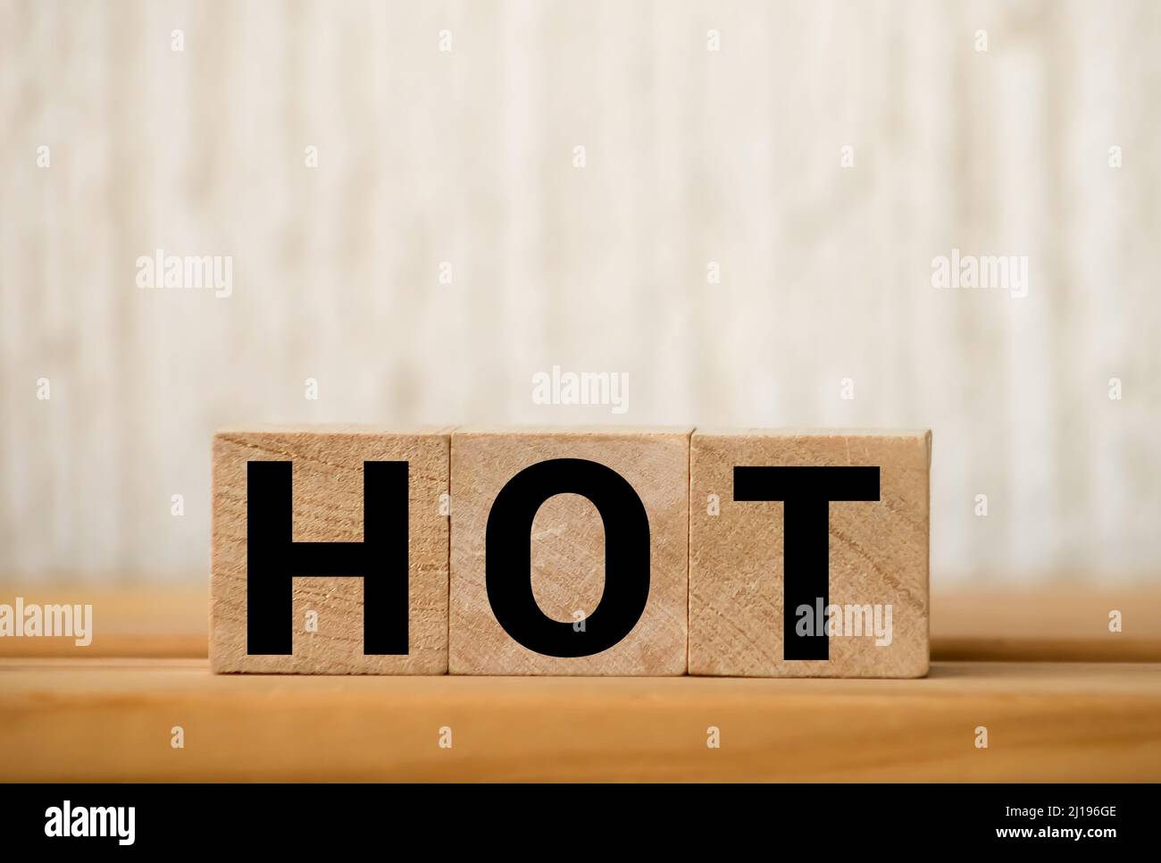 HEISSES Wort auf Holzklötze geschrieben und auf einem gelben gesetzt. Vakanz, Verkauf und Hot Seat Konzept Stockfoto