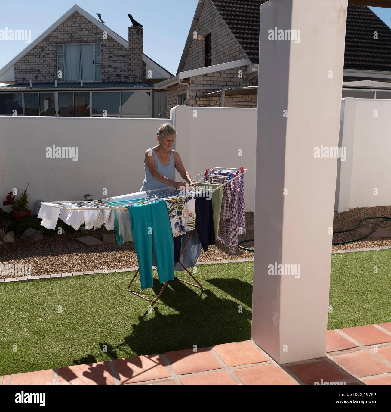 Südafrika. 2022. Ältere Frau, die an einem sonnigen Tag im Garten auswaschen und trocknen kann. Stockfoto