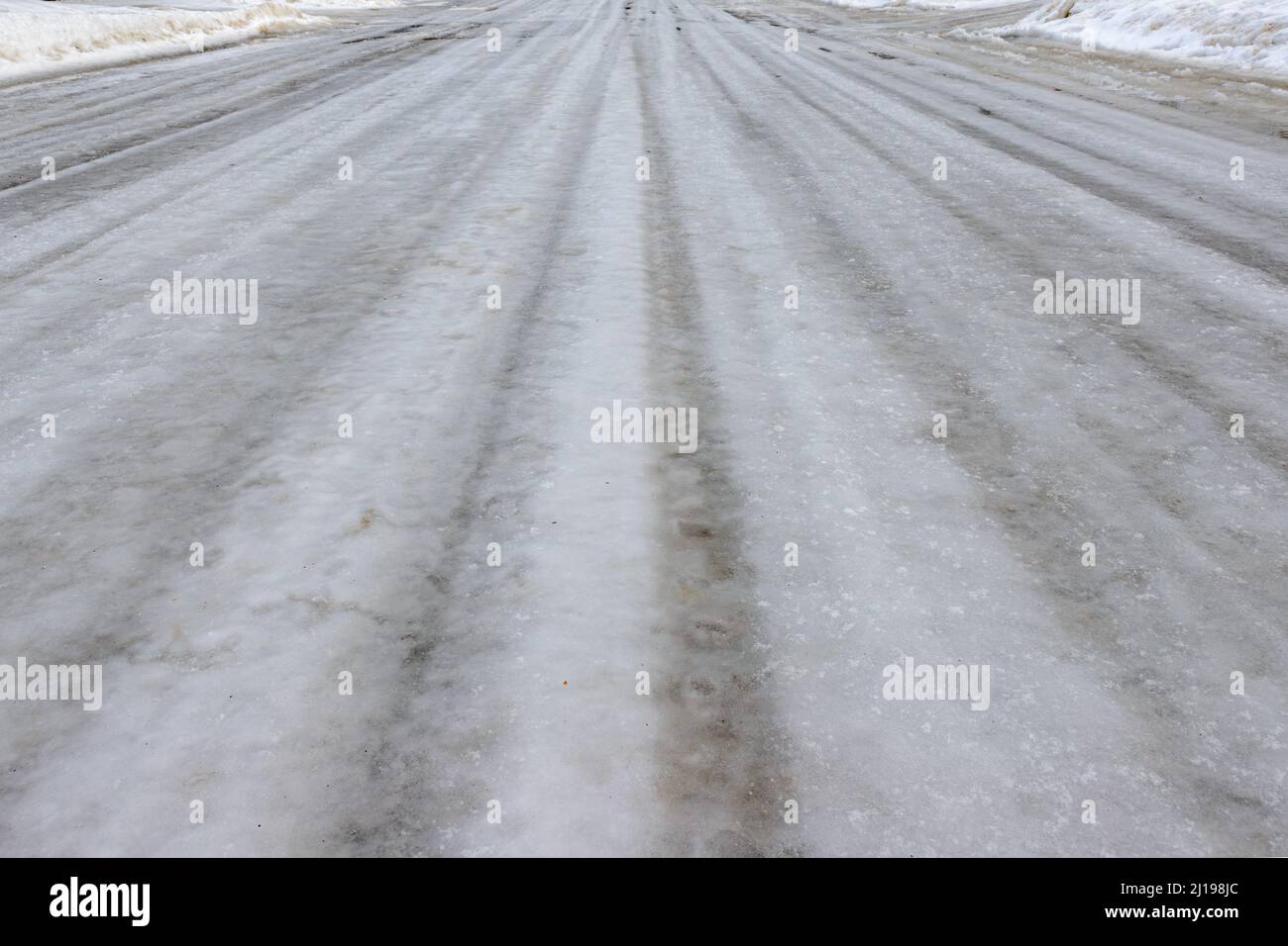 Ein niedriger Winkel Ansicht einer eisbedeckten Straße.die Straße ist vollständig mit Eis bedeckt, und das Eis hat Rillen in ihm durch den vorbeifahrenden Verkehr getragen. Stockfoto