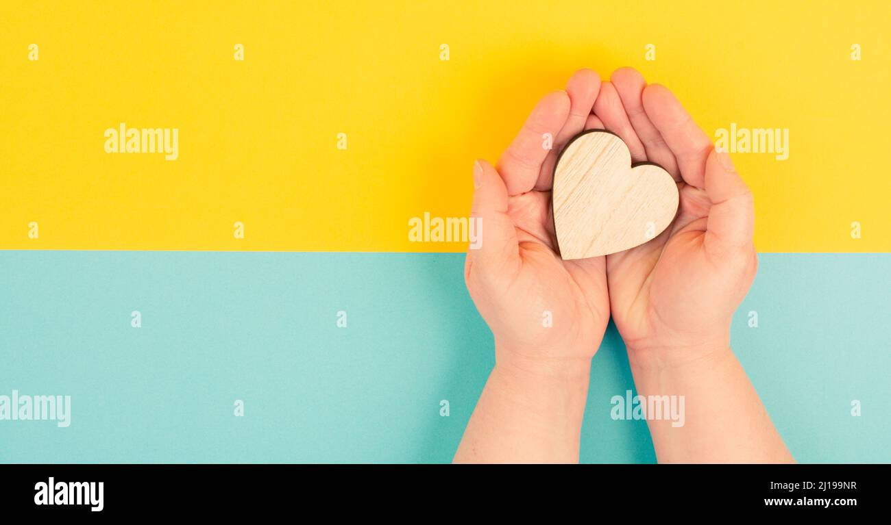 Frau hält ein rotes Herz in der Hand, blauer Hintergrund, Kopierraum, Liebe und Nächstenliebe Symbol, Hoffnung Konzept Stockfoto