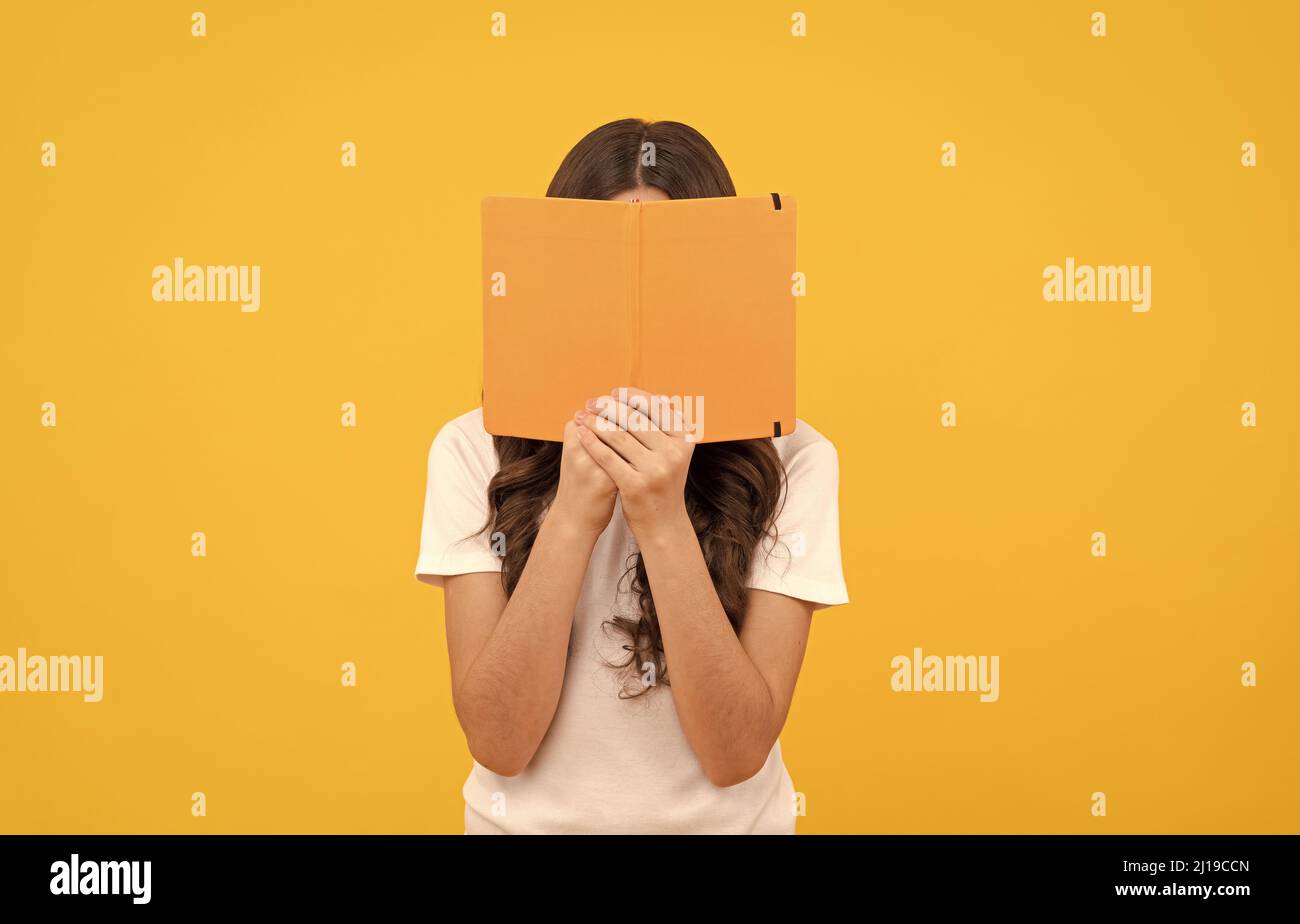 Lächelndes Schulkind bereit zu studieren verstecken sich hinter Buch, Wissen Stockfoto