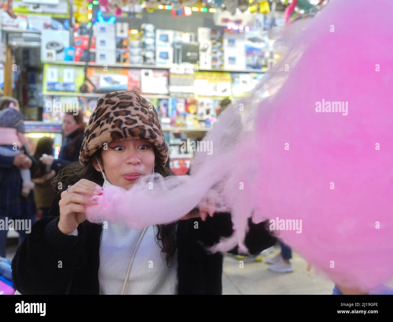 Glückliche Frau, die in einem Vergnügungspark eine Zuckerwatte isst Stockfoto