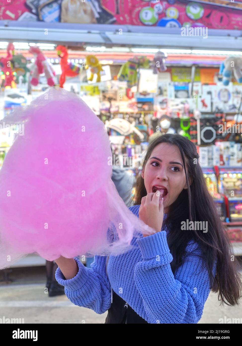 Latina-Frau, die auf einem Nachtmarkt eine Zuckerwatte isst Stockfoto