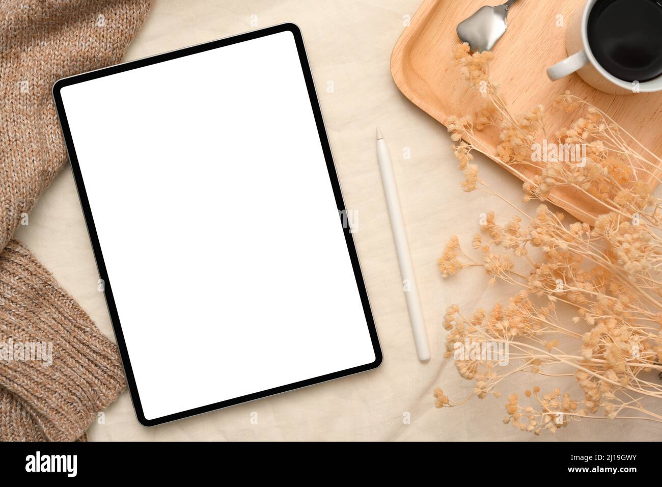 Minimal gemütliche Ästhetik beige Hintergrund mit digitalen Tablet weißen Bildschirm Mockup, getrocknete Blumen, Kaffee-Set und braune Decken. Draufsicht Stockfoto