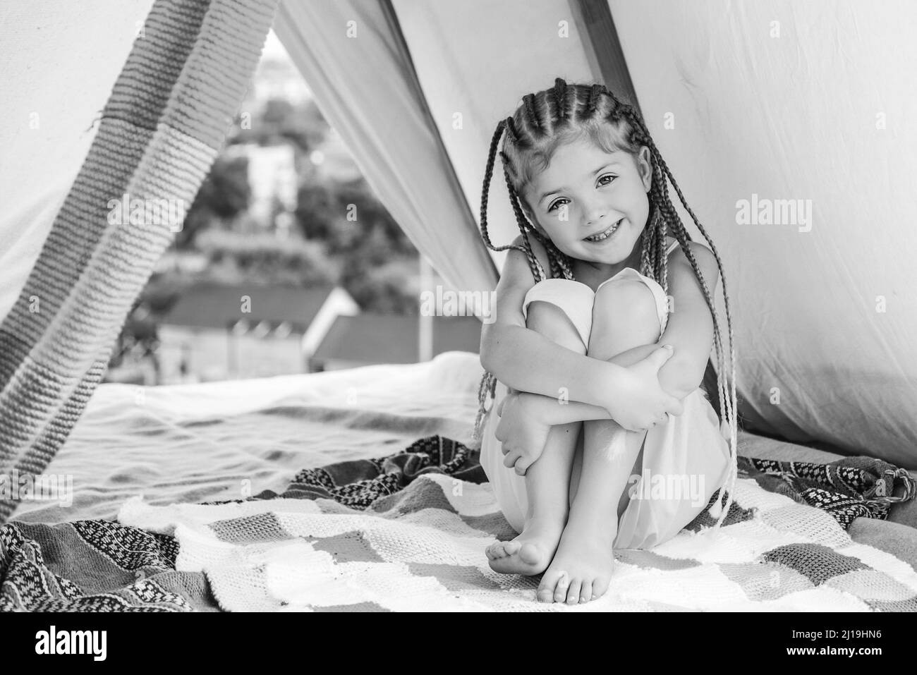 Camping für Kinder. Spaß im Freien. Campingplatz. Kleines Mädchen mit Dreadlocks Lager mit Zelt. Aktiver Lebensstil von Kindern. Stockfoto