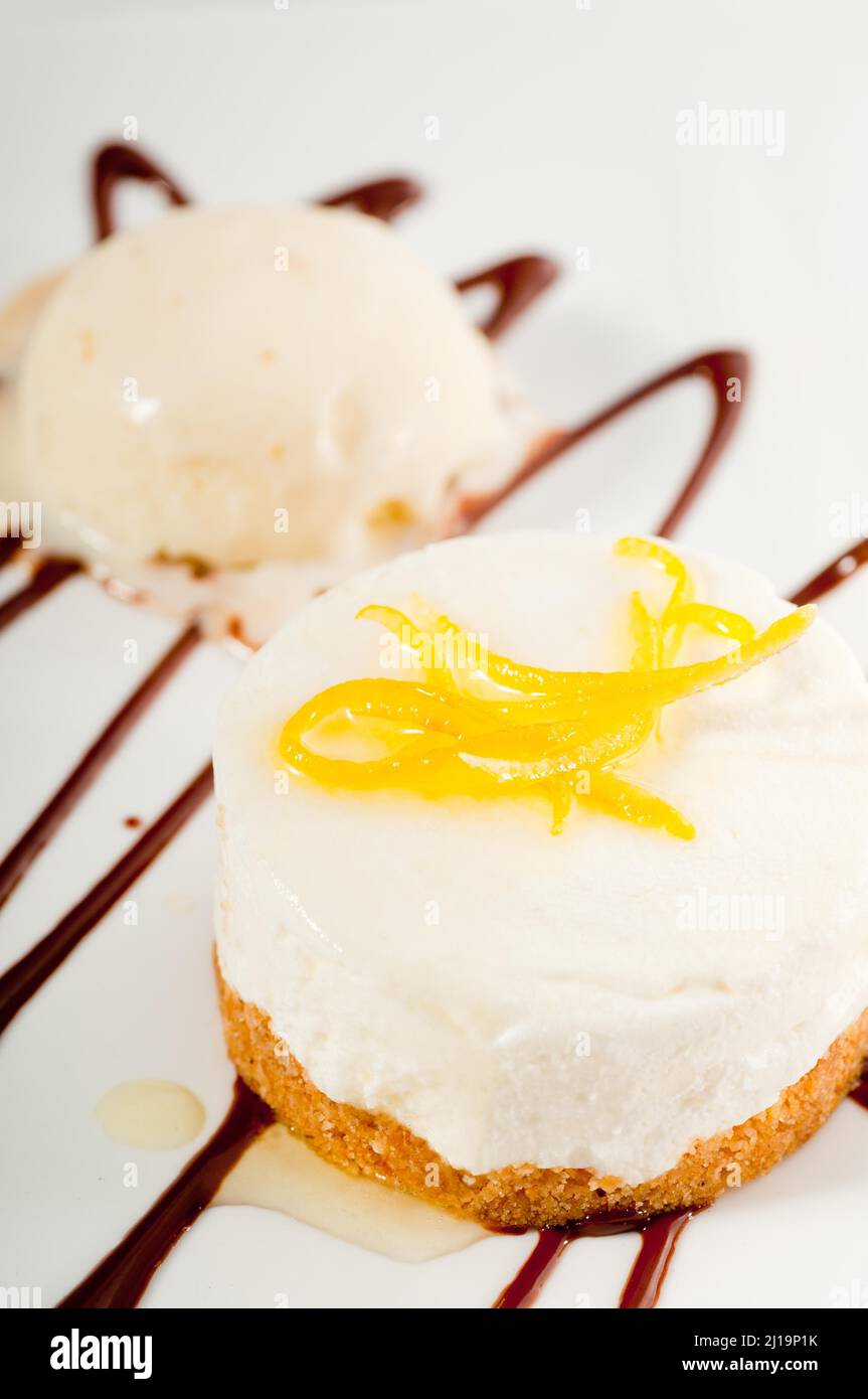 Sehr elegantes Dessert mit Zitronenmousse, Zitronenschale auf der Oberseite und Vanilleeis auf der Seite Stockfoto