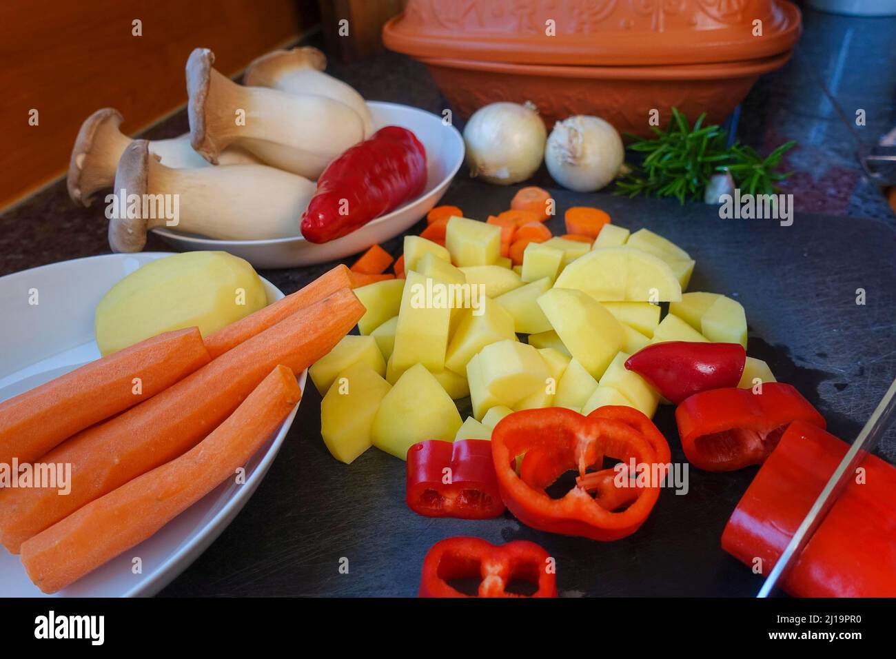 Süddeutsche Küche, Gemüse aus dem römischen Topf zubereiten, Gemüse schneiden, rote Paprika, Karotten, gewürfelte Kartoffeln, Pilze, Kräuter Stockfoto