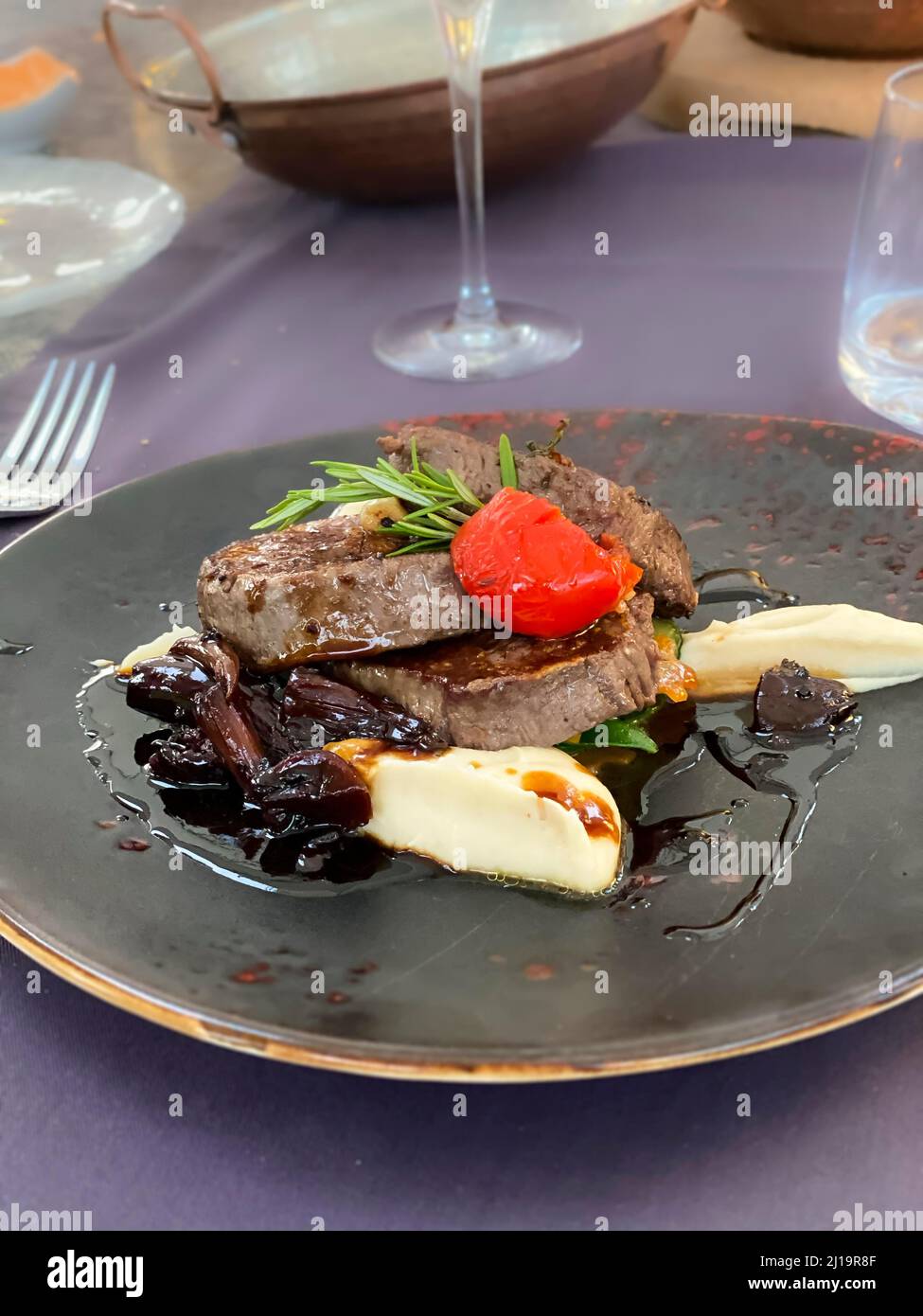 Steak mit Pflaumenmarmelade, Kartoffelpüree, Tomaten und Rosmarin Stockfoto