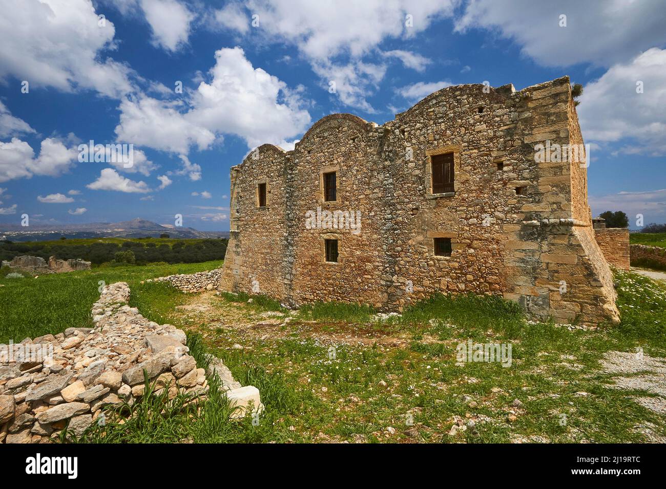 Frühling auf Kreta, dreischiffiger Klosterbau aus dem frühen Mittelalter, Steinmauer, blauer Himmel mit Schönwetterwolken, man kann die Akrotiri sehen Stockfoto