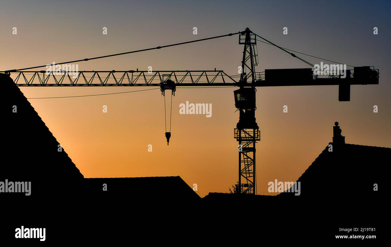 Silhouette eines Baukran im Abendlicht, über Hausdächern, Wolfhausen, Schweiz Stockfoto