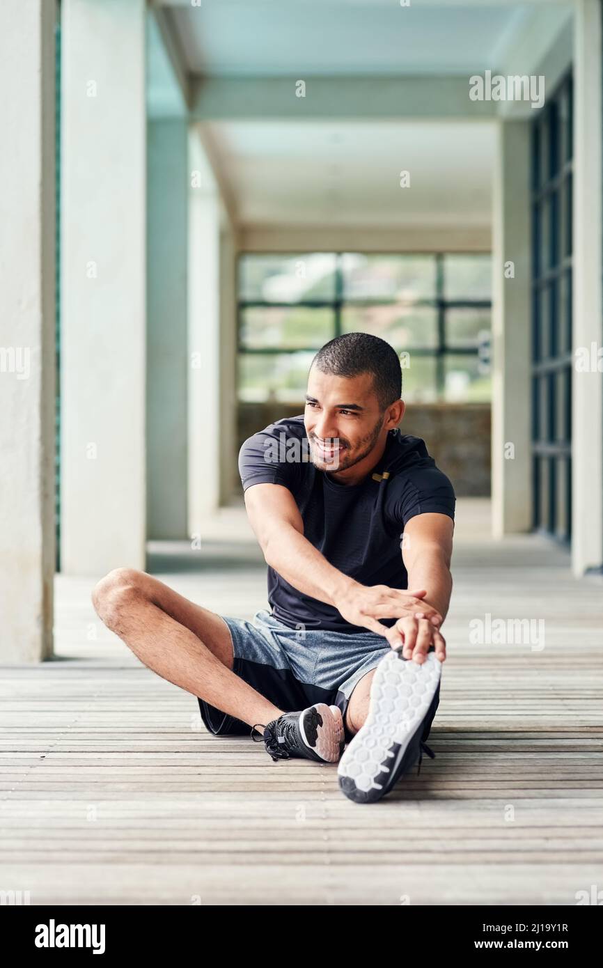 Verpflichtet, gesund und in Form zu bleiben. Aufnahme eines sportlichen jungen Mannes, der sich draußen ausdehnt. Stockfoto