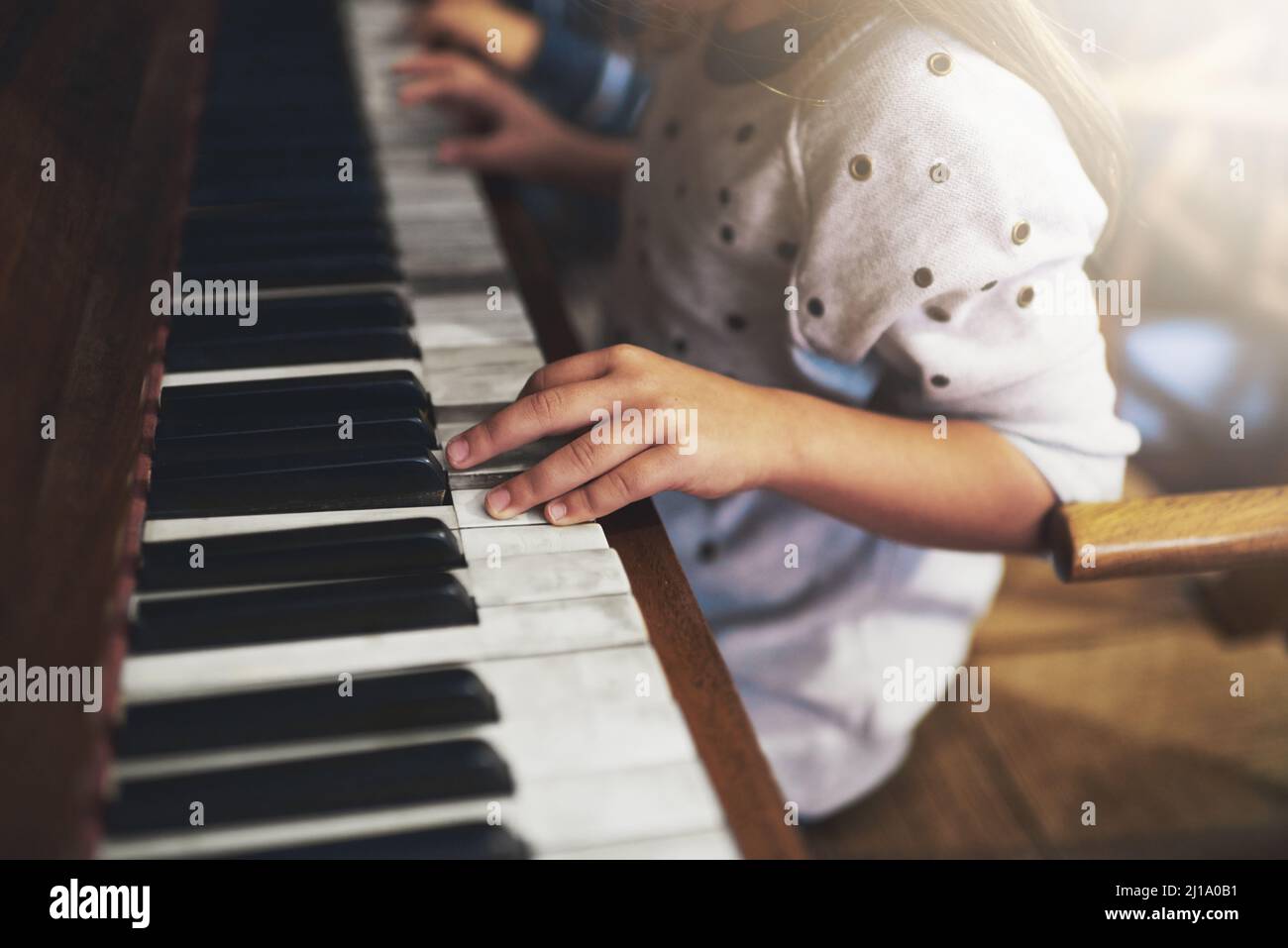 Klaviere erschließen die Schlüssel zum Talent im Kindesalter. Eine kleine Aufnahme eines kleinen Mädchens, das Klavier spielt. Stockfoto