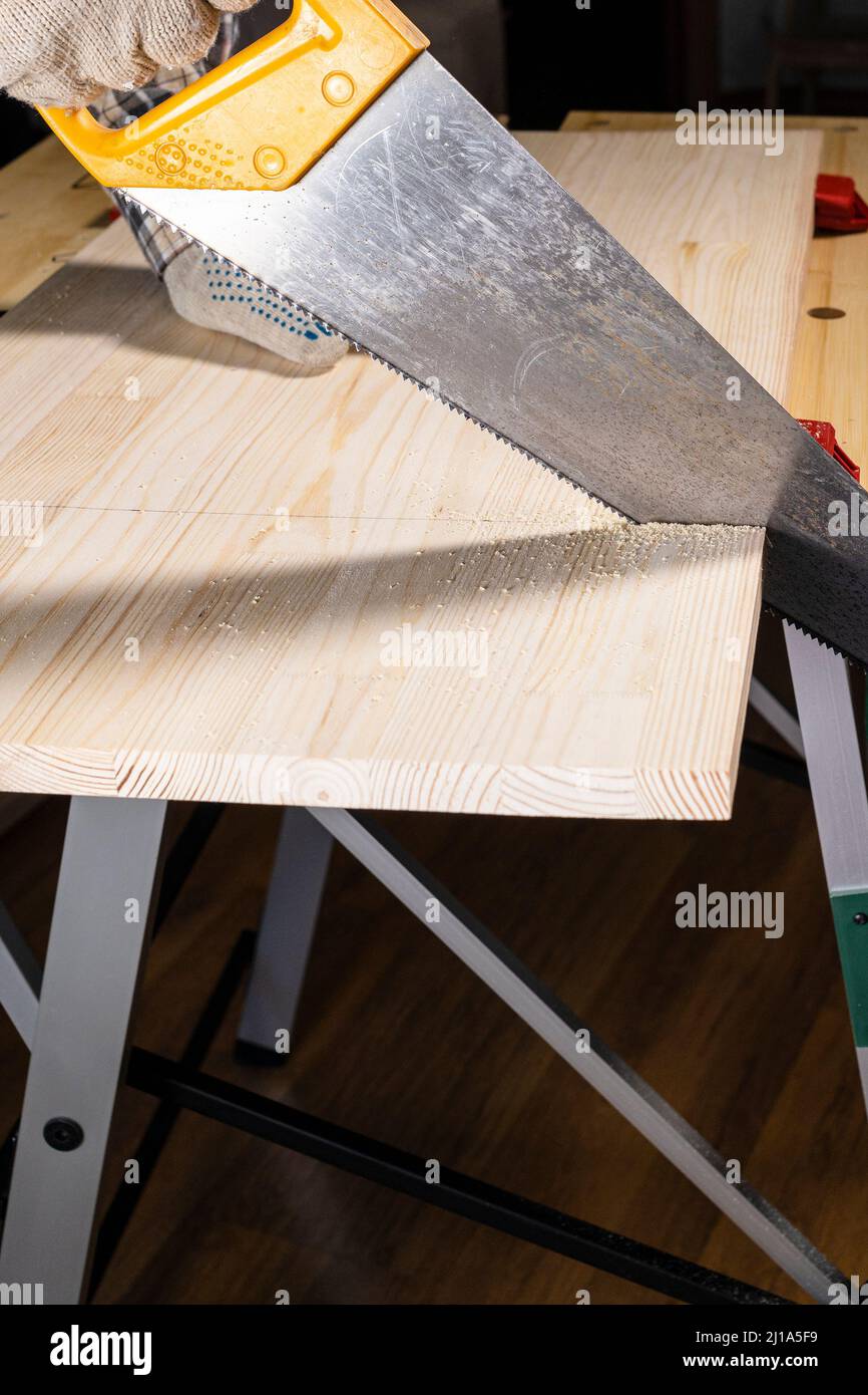 Seitenansicht der Zimmermannssägen Holzbrett mit Handsäge auf der Werkbank zu Hause Stockfoto