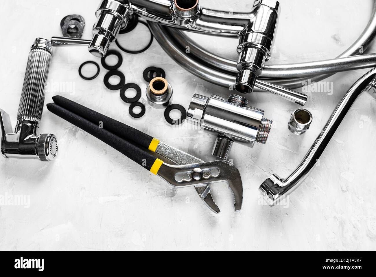 Ansicht von Schraubenschlüssel und zerlegtem Duschhahn auf Betonplatte Stockfoto