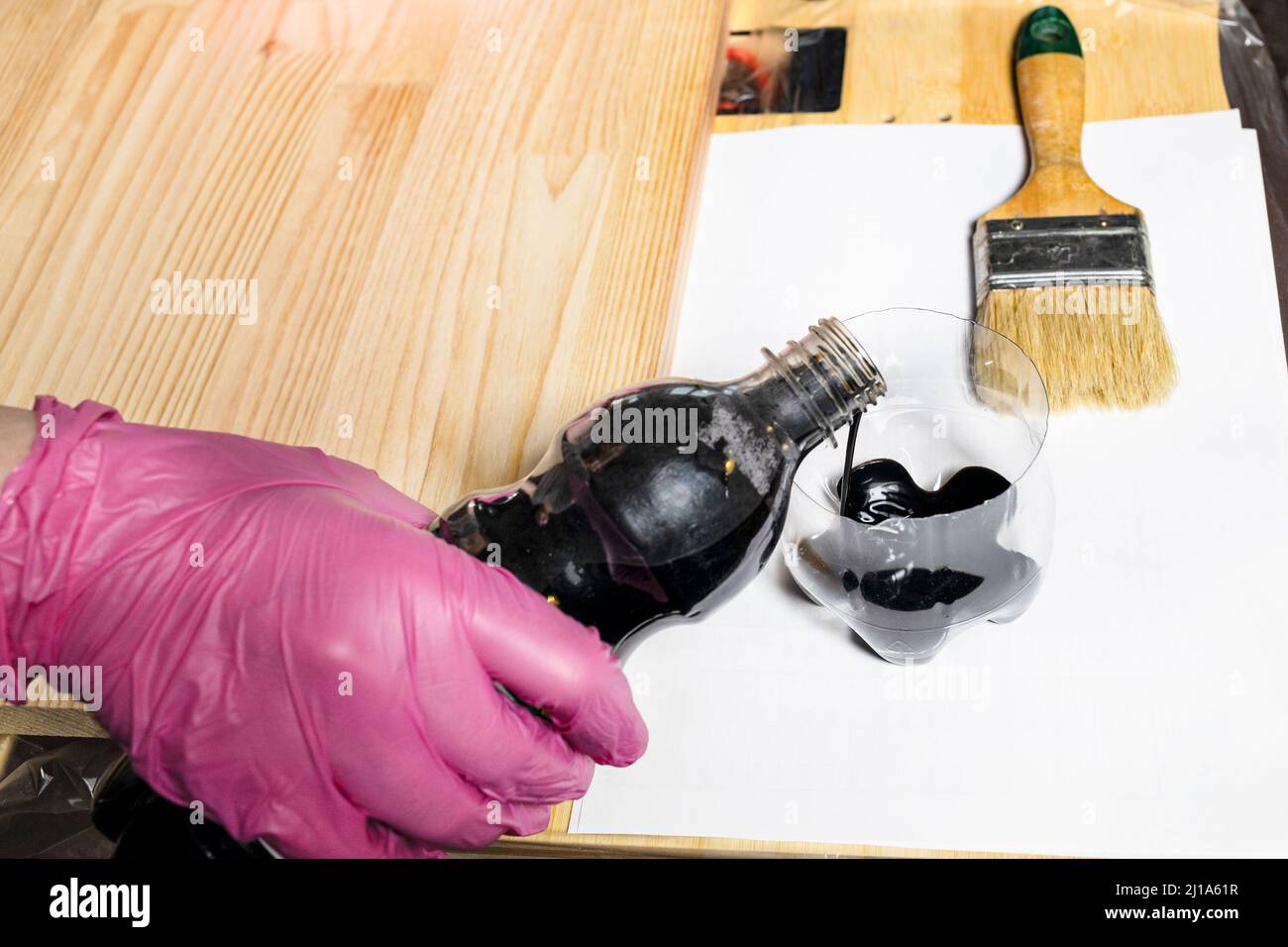 Handschaufel gießt Holzfleck aus der Flasche in ein Glas auf Holzbrett zu Hause Stockfoto