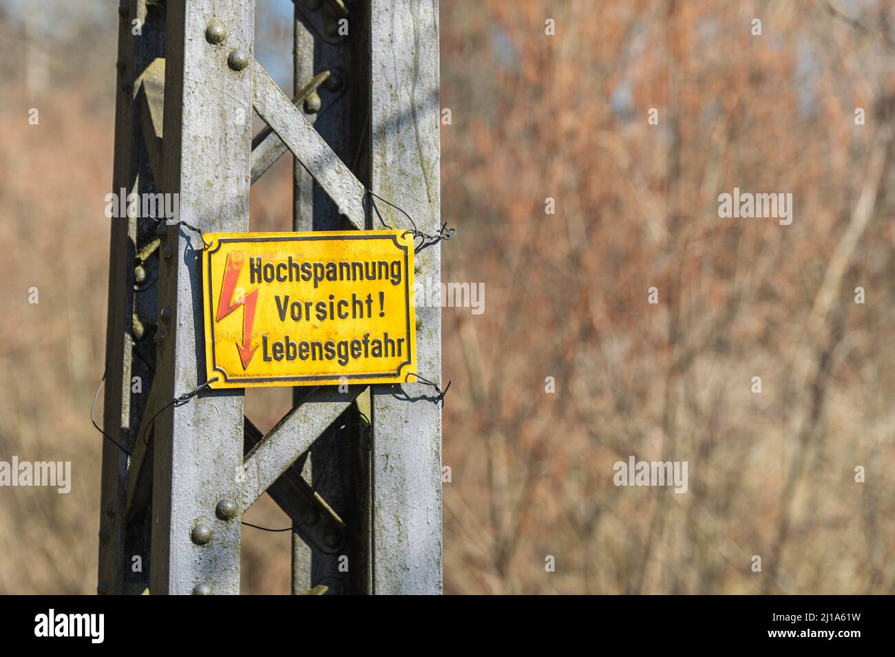 Ein Schild auf einem Pol mit der deutschen Aufschrift , Hochspannung Achtung Lebensgefahr Stockfoto