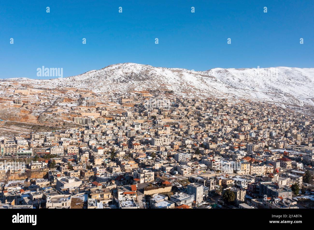 Hermon Bergrücken bedeckt mit Schnee im Winter 2022, mit den Stadthäusern von Majd al Shams. Stockfoto